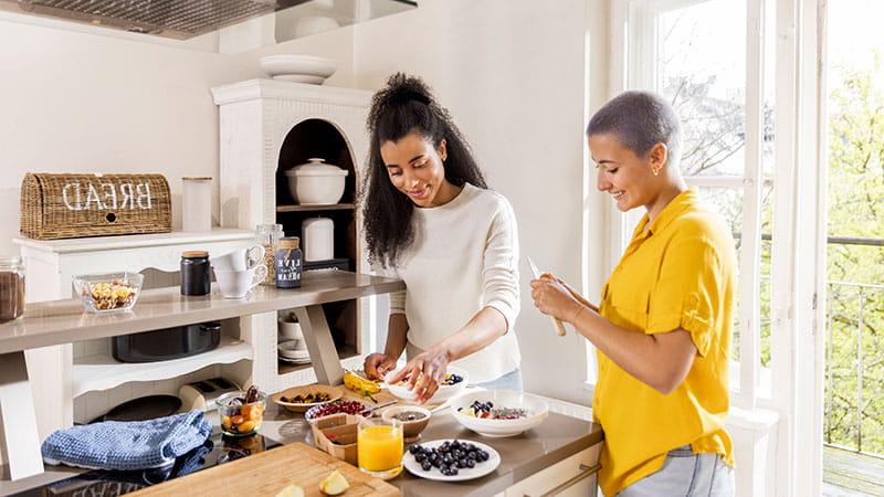 Two young women making a healthy breakfast in the kitchen.